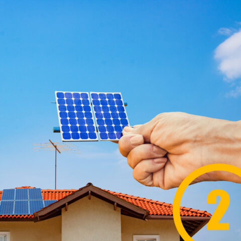 hand holding solar cell up to house