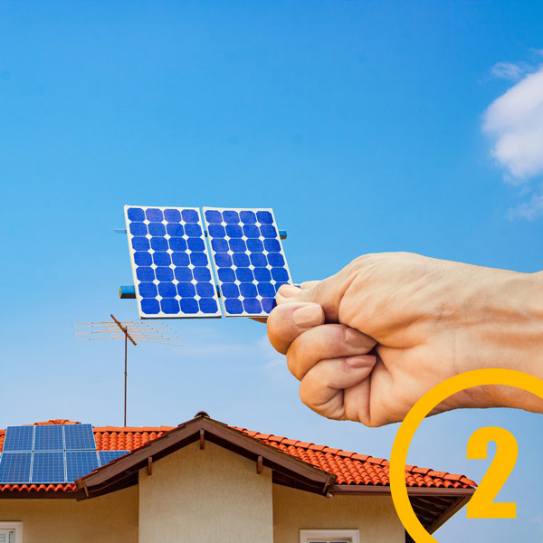 hand holding solar cell up to house