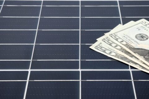 Dollar bills on solar panels showing energy savings in Atlanta, GA