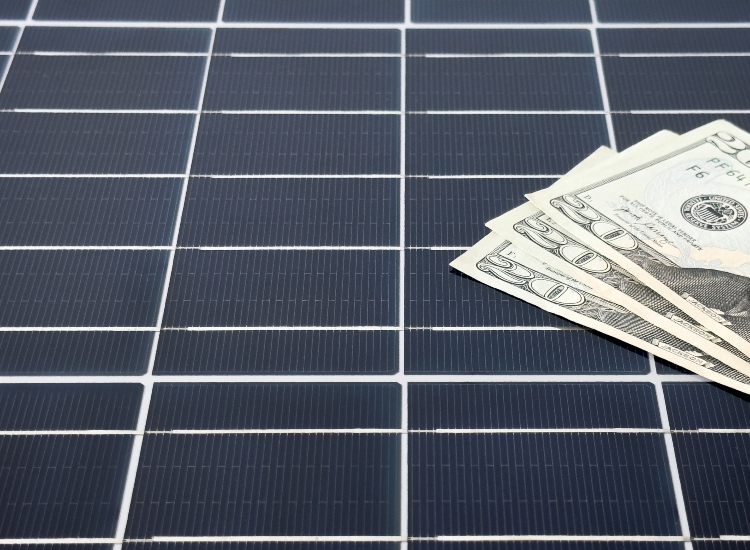 Dollar bills on solar panels showing energy savings in Atlanta, GA